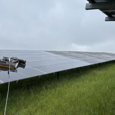 Solarreinigungsroboter bei der Reinigung einer großflächigen Photovoltaikanlage im Grünen.